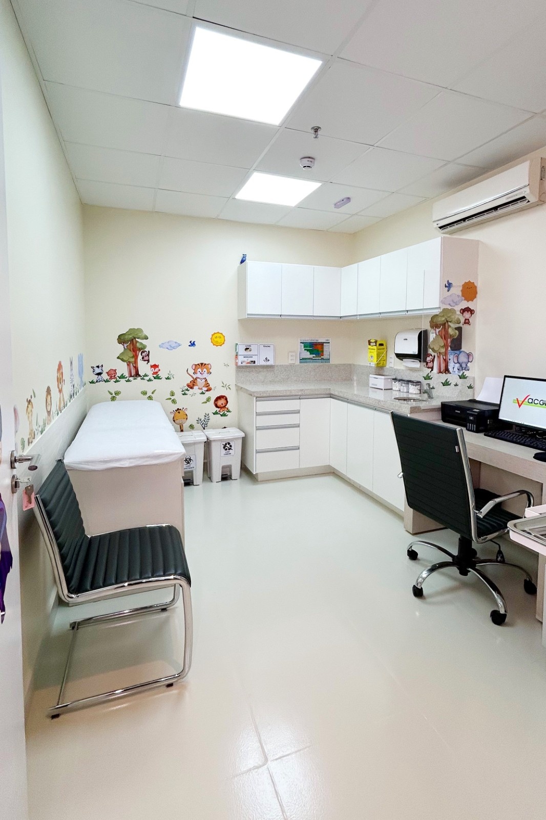 Sala de vacinação infantil da Vaccine Care Arujá, com maca e adesivos de animais